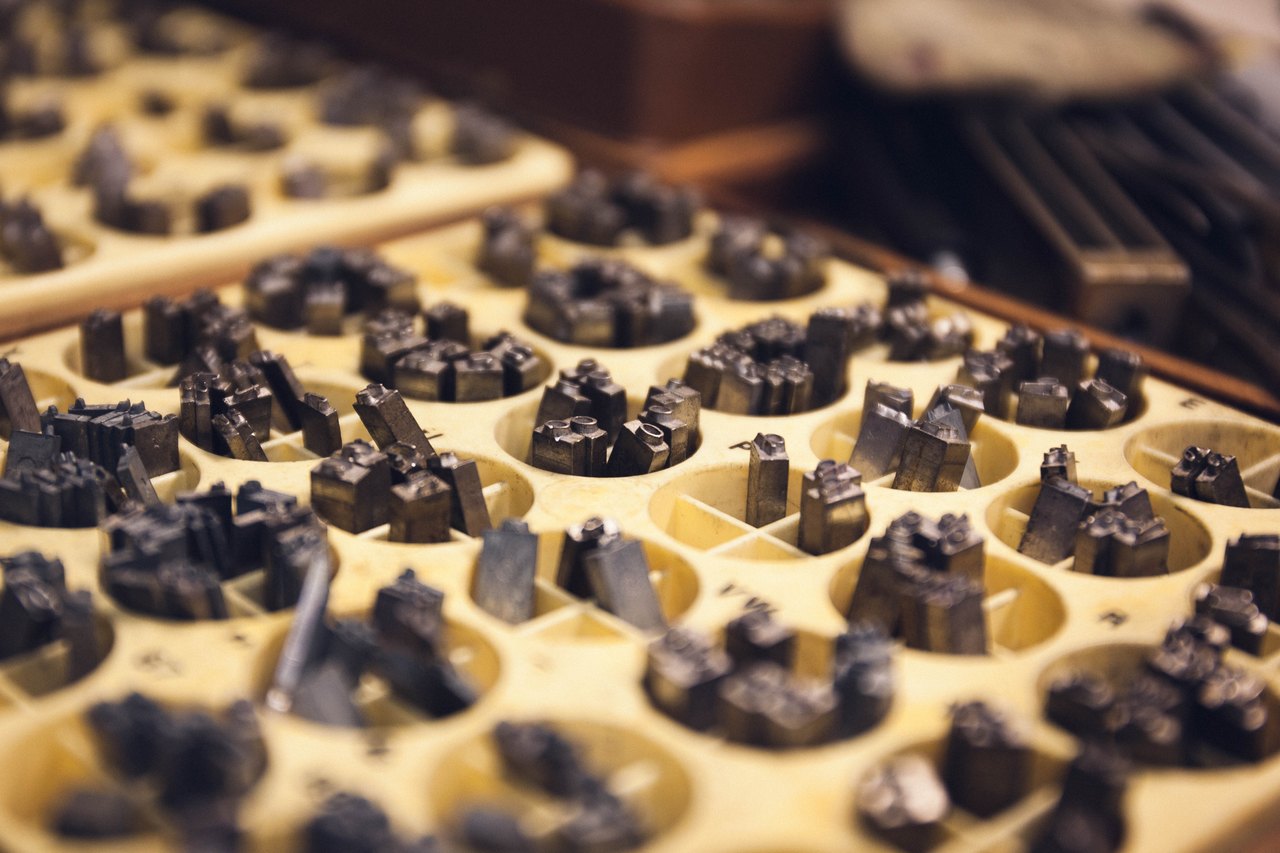 A printer's type case seen close up, dozens of small compartments holding metal letters standing on end