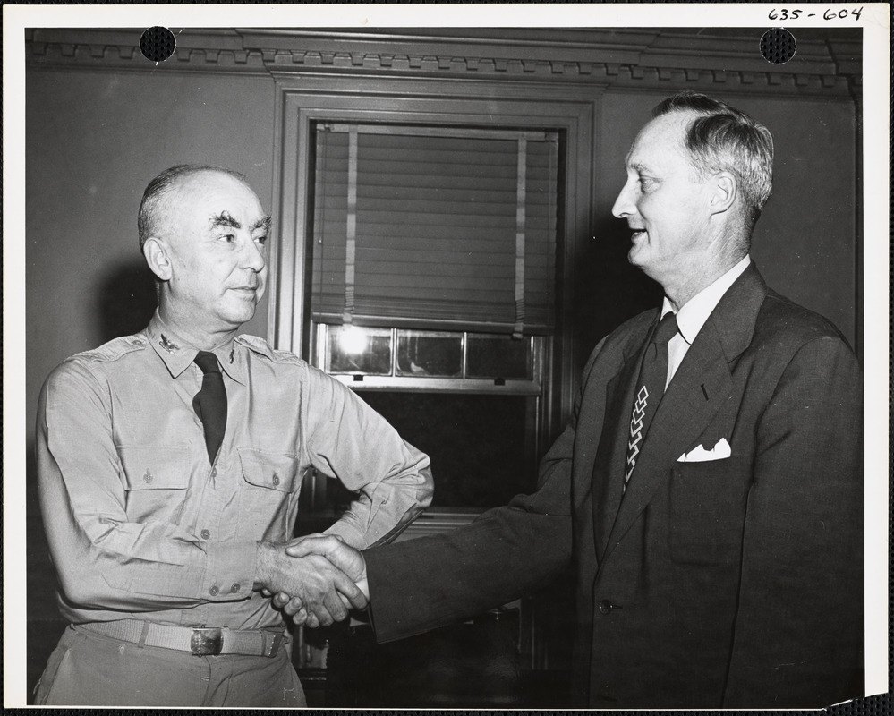 Black-and-white photograph of two men shaking hands beside a window, one in a military uniform and one in a dark civilian suit, both smiling
