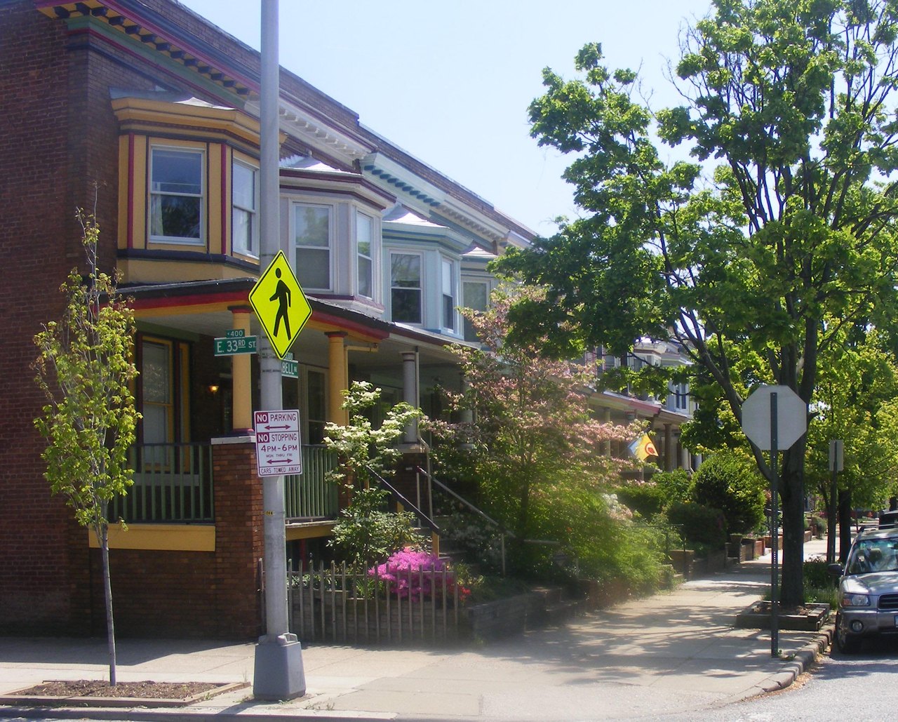A row of joined brick houses along a tree-lined street, each with its own porch, front steps and door