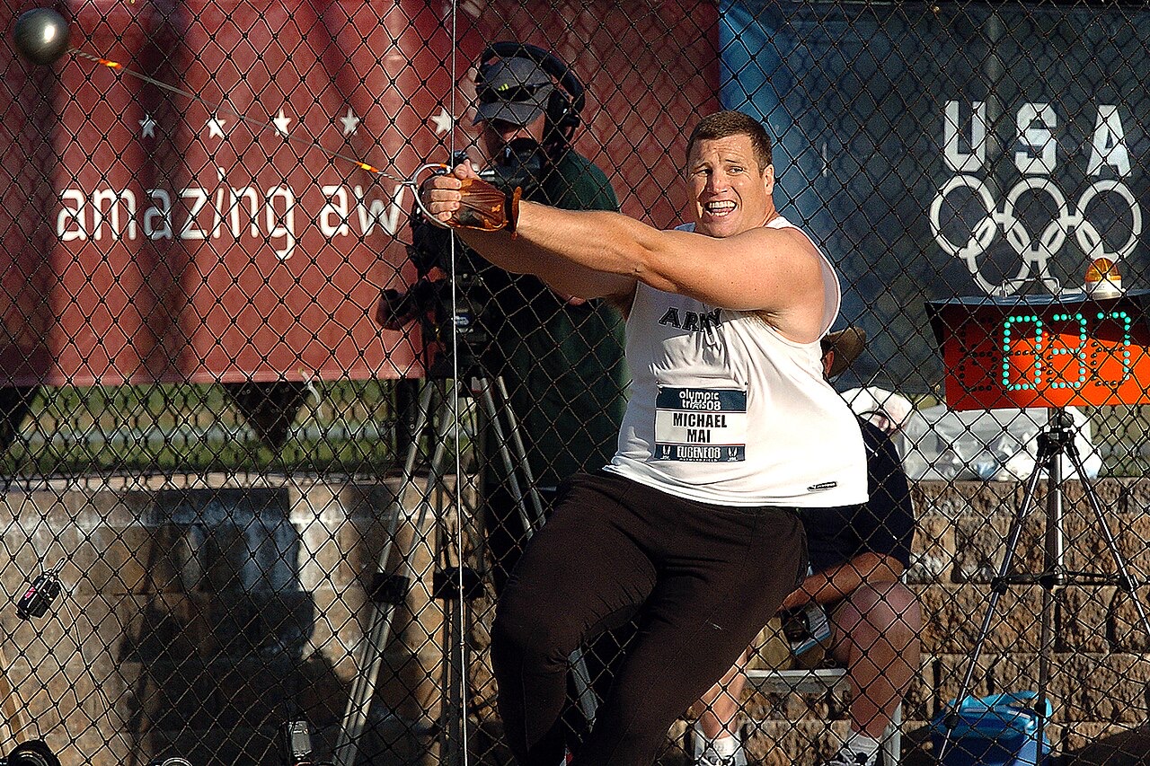 An athlete in mid-spin inside a throwing circle, the hammer's wire and ball stretched out behind him