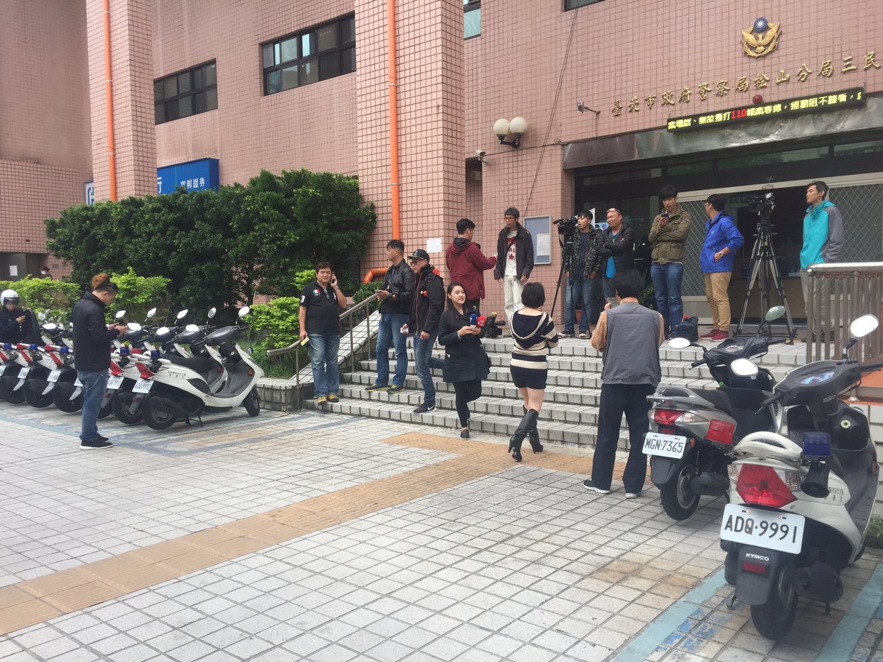 A line of television crews with cameras on tripods waiting on the steps outside a public building