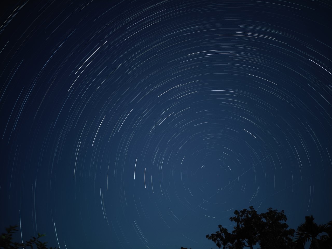 A long-exposure night photograph in which the stars have drawn concentric circular arcs around a single point in the sky