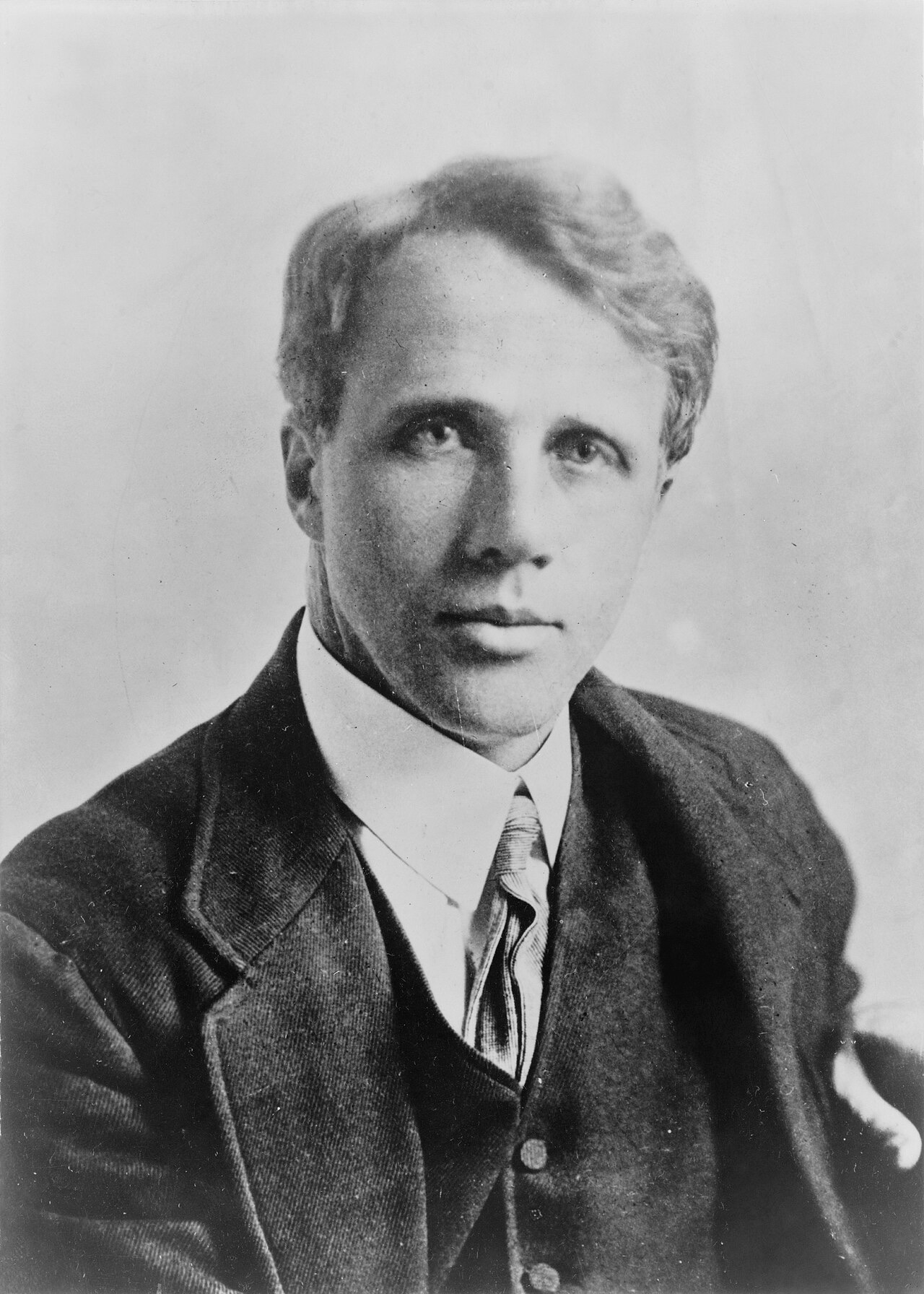 A black-and-white head-and-shoulders portrait of a middle-aged man in a tweed jacket, vest and striped tie, with light combed hair and a steady, level gaze