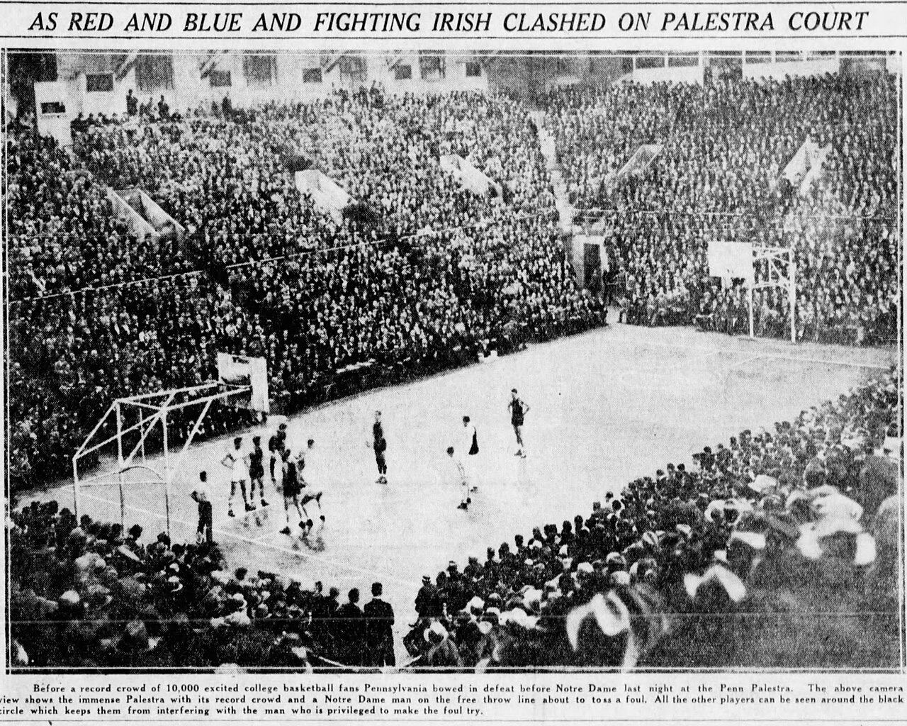 A grainy 1929 newspaper photograph of a vast indoor basketball arena, every seat filled, players standing on the court during a free throw