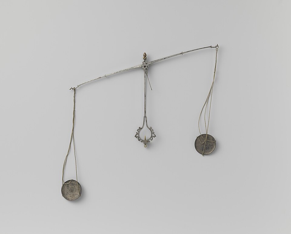 A slender silver balance hanging against a pale gray background, its beam tipped so that one round pan on cords hangs lower than the other