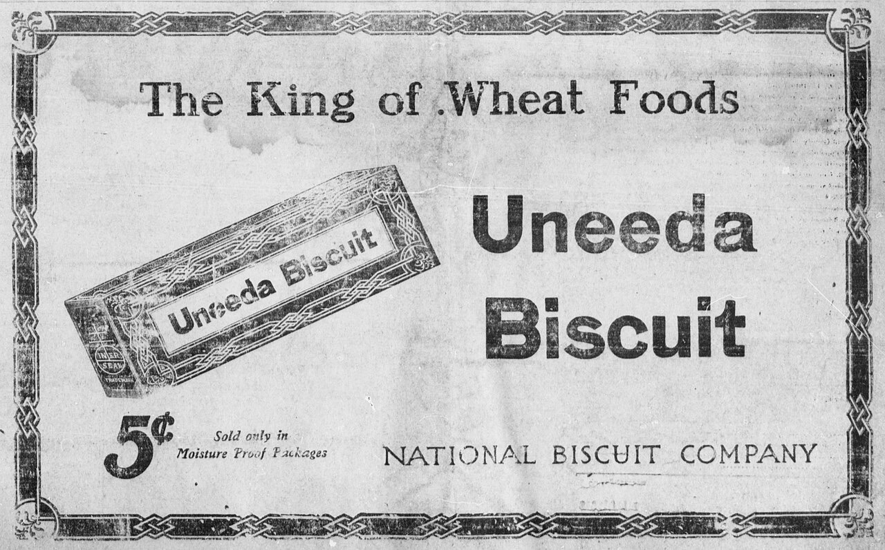 A grainy 1910s newspaper advertisement: a slanted box of Uneeda Biscuit crackers, the slogan The King of Wheat Foods, a five-cent price, and the name National Biscuit Company