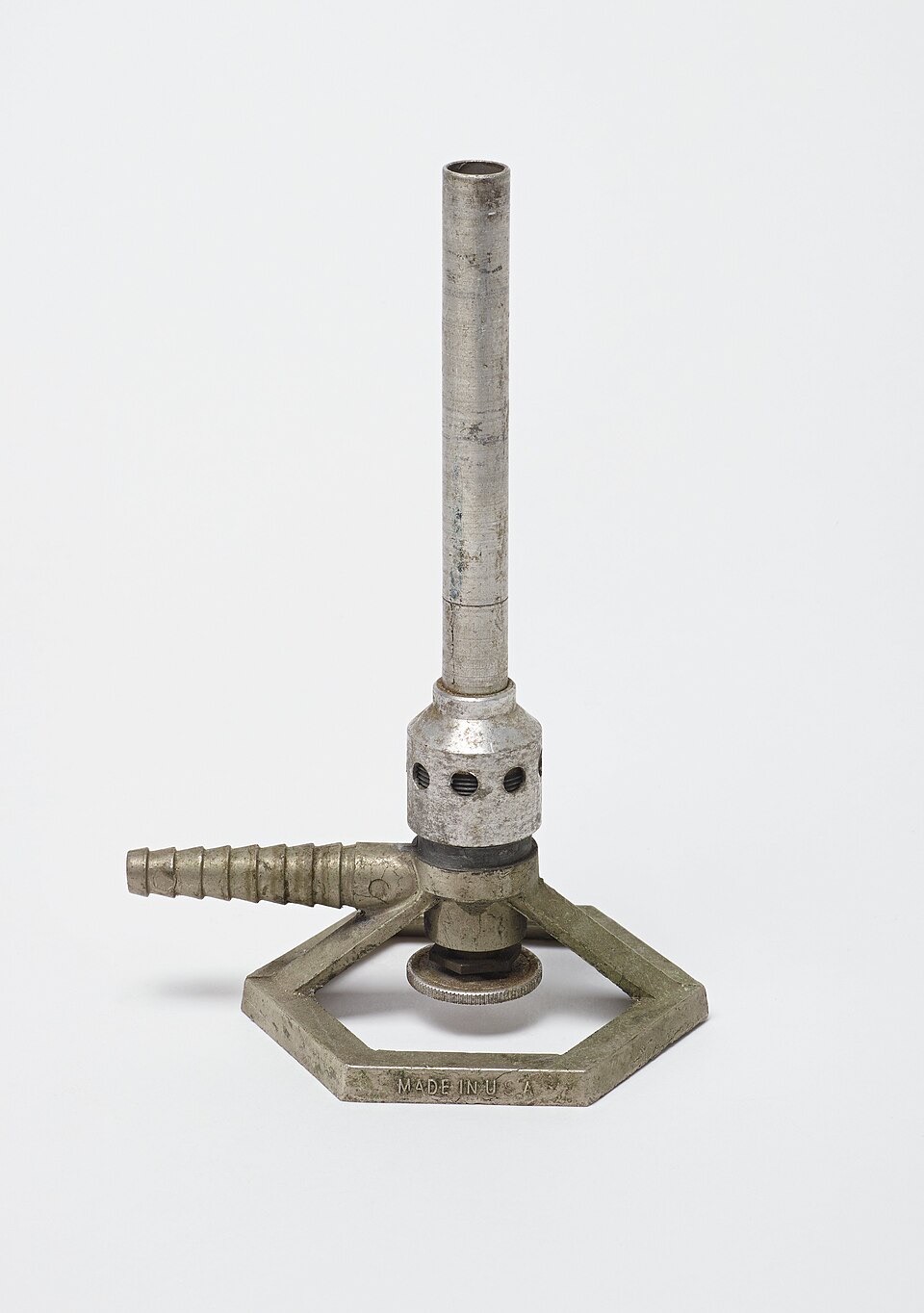 A nickel-plated Bunsen burner: a hexagonal base, a side tube for the gas, and a tall metal barrel