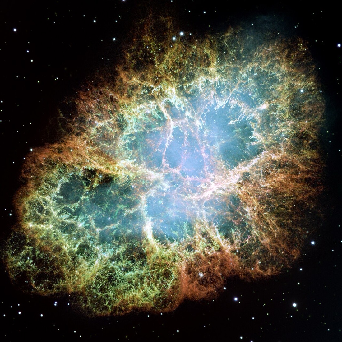 A tangled cloud of orange and green filaments around a glowing blue centre, against black space with scattered stars