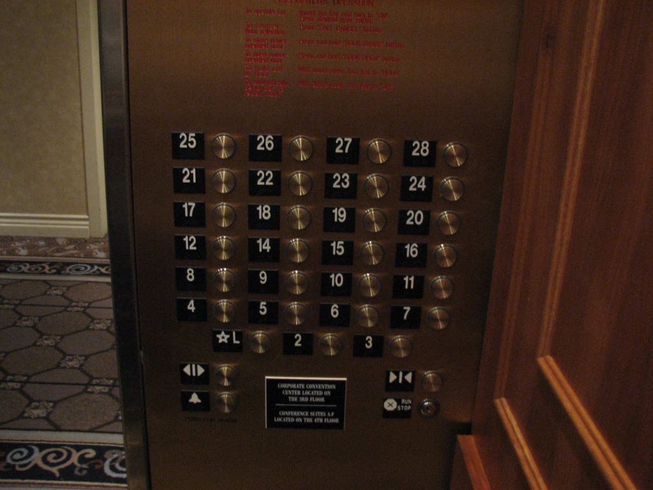 A brass elevator control panel with rows of numbered buttons; the numbers run 8, 9, 10, 11, then 12, 14, 15, 16, with no button for 13